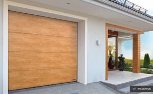 A modern home entrance with a wooden garage door, stone path, and plant decorations.